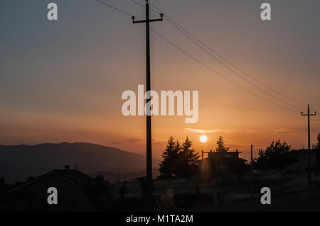 Poteaux électriques Le courant traversant la ligne contre un ciel clair au coucher du soleil à Oratino campagne, Campobasso, Molise, Italie. country house silhouette Banque D'Images