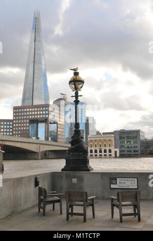 Une table et des chaises sous un lampadaire avec une mouette assis sur le dessus avec le tesson office building et le nombre 1 1 London Bridge en arrière-plan. Banque D'Images