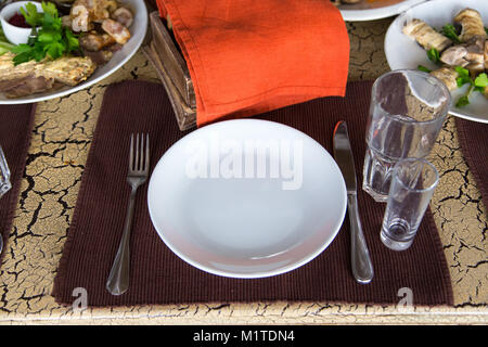 Sur la serviette marron, sur la table est couverts par personne, fourchette, couteau, deux verres, sur l'arrière-plan il y a des rouleaux de l'aubergine grillée et vegetabl Banque D'Images
