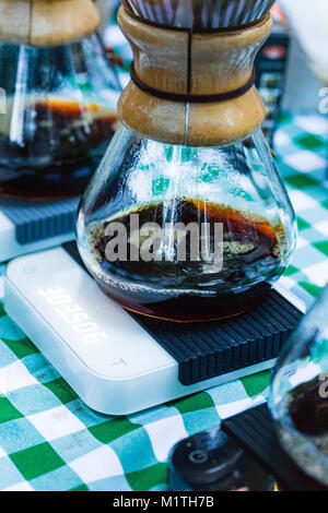 Verser sur les gouttes de café en artisanat du verre brewers assis sur une balance électronique tandis que l'extérieur, sur une table de pique-nique Banque D'Images