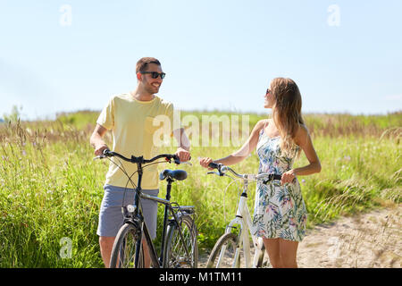 Couple heureux avec des vélos sur route de campagne Banque D'Images