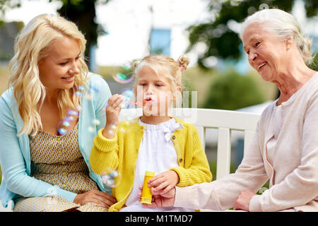 Happy Family blowing soap Bubbles at park Banque D'Images