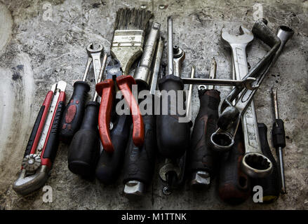 Un workbench en désordre plein de vieux outils graisseux fixés pour la réparation ou l'entretien la pendaison ou portant sur un banc dans un garage Banque D'Images