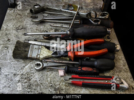 Un workbench en désordre plein de vieux outils graisseux fixés pour la réparation ou l'entretien la pendaison ou portant sur un banc dans un garage Banque D'Images