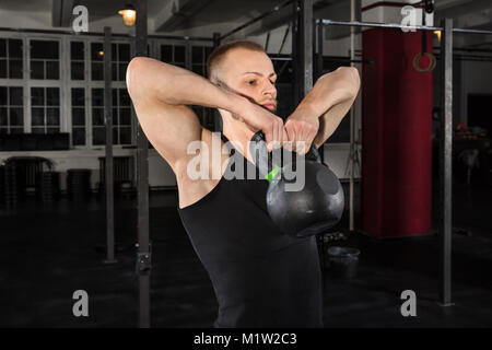 Portrait d'un athlète Man Exercising With électrique Bell dans la salle de sport Banque D'Images