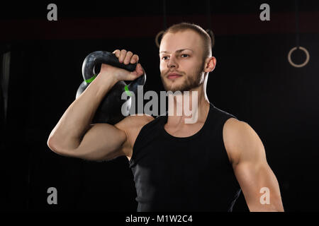 Portrait d'un athlète Man Exercising With électrique Bell dans la salle de sport Banque D'Images