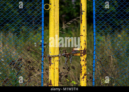 Rusty clôture verrouillée avec un cadenas et chaîne de protection d'une propriété abandonnée Banque D'Images