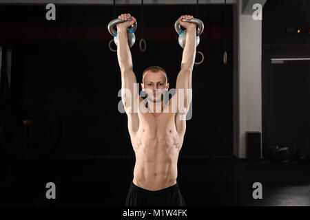 Vue arrière d'un jeune athlète homme faire de l'exercice avec électrique Bell dans la salle de sport Banque D'Images