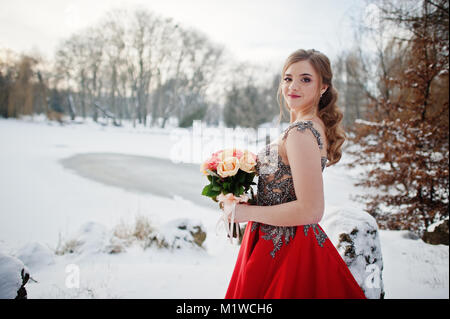 Superbe fille avec bouquet d'élégance robe rouge à la journée d'hiver. Banque D'Images