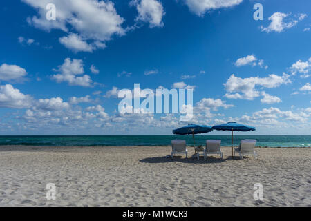 USA, Florida, Miami beach vide avec deux parasols bleus et trois chaises en face de l'océan bleu Banque D'Images