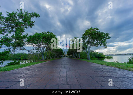 USA, Floride, le chemin de pavé par allée de vieux arbres entre l'eau avec le drapeau des Etats-Unis derrière Banque D'Images