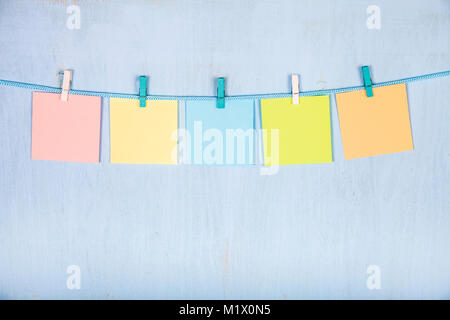 Cinq feuilles de papier accrocher sur une corde sur un fond en bois bleu. Banque D'Images