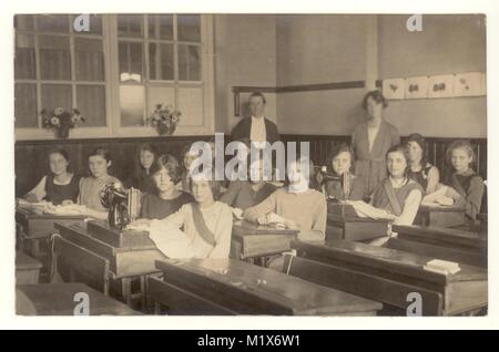 Début des années 1920 Carte postale de jeunes filles en âge de fréquenter l'école secondaire assis à un bureau avec des machines à coudre, de porter leurs propres vêtements, 1920, Royaume-Uni Banque D'Images