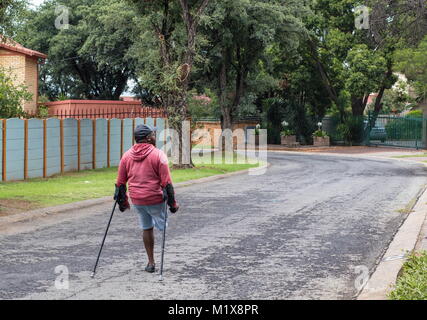 Johannesburg, Afrique du Sud - l'homme physiquement handicapés non identifiés sur des béquilles lutte dans les rues de la ville, image au format paysage Banque D'Images