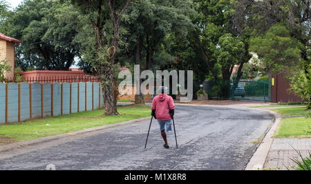 Johannesburg, Afrique du Sud - l'homme physiquement handicapés non identifiés sur des béquilles lutte dans les rues de la ville, image au format paysage Banque D'Images