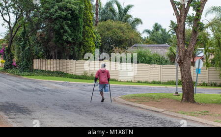 Johannesburg, Afrique du Sud - l'homme physiquement handicapés non identifiés sur des béquilles lutte dans les rues de la ville, image au format paysage Banque D'Images