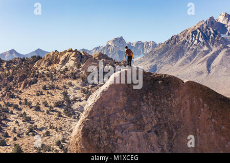 L'homme grimpe sur rocher de granit énorme rocher dans la région de babeurre de Bishop, en Californie avec la Sierra Nevada derrière Banque D'Images