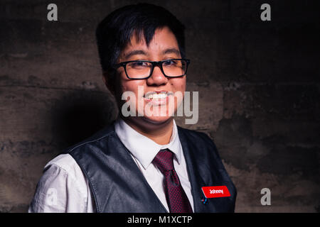 Jeune homme transgenre en vêtements officiels avec un semi style bondage cuir gilet pose dans un emplacement grungy urban Banque D'Images