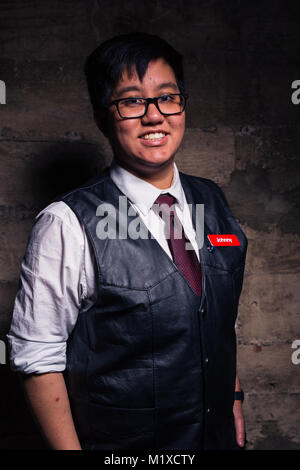 Jeune homme transgenre en vêtements officiels avec un semi style bondage cuir gilet pose dans un emplacement grungy urban Banque D'Images