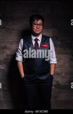 Jeune homme transgenre en vêtements officiels avec un semi style bondage cuir gilet pose dans un emplacement grungy urban Banque D'Images