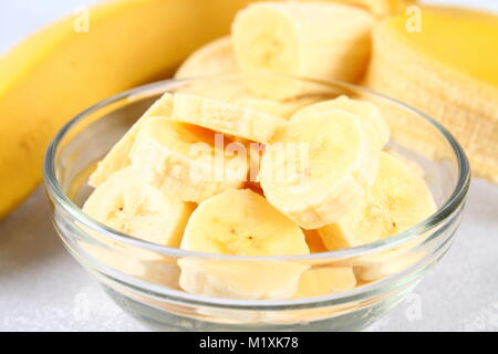 Les bananes sont ensemble et couper sur une tranche dans une tasse sur fond gris Banque D'Images