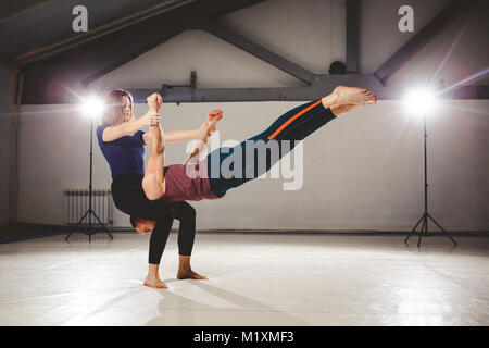 Le thème de l'Acroyoga et postures de yoga. Acroyogis la pratique. avec le studio de rétroéclairage. La femme garde l'homme de base circulaire en position horizontale S Banque D'Images