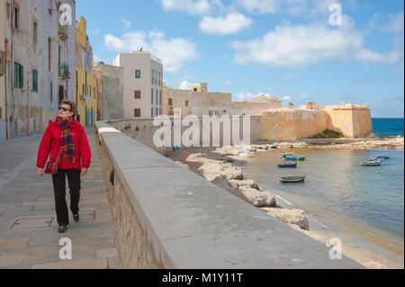 Trapani Sicile mur de mer, vue d'une femme mûre simple marchant le long du mur de mer dans le port de Trapani, Sicile (MODÈLE LIBÉRÉ) Banque D'Images