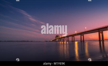 Une longue exposition prises pendant l'heure bleue de l'incendie d'entrée de l'île pont avec les lumières sur la capture le reflet dans l'eau calme et nuage rose Banque D'Images