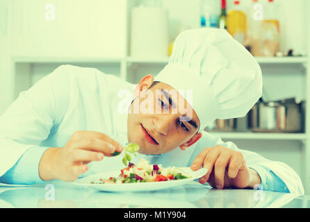 Cuisinier professionnel est degustating sur salade de cuisine. Banque D'Images