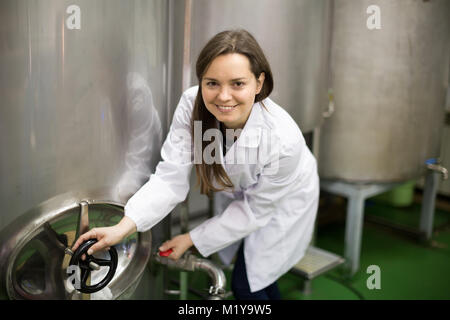 Souriante jeune femme près de baquet d'huile d'olive dans l'environnement de fabrication Banque D'Images