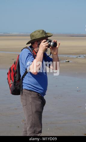 Photographe d'âge moyen de prendre une photo à Westward Ho ! Sandy Beach, North Devon, UK. Banque D'Images