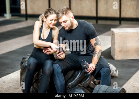Couple à l'aide de téléphone dans la salle de sport Banque D'Images