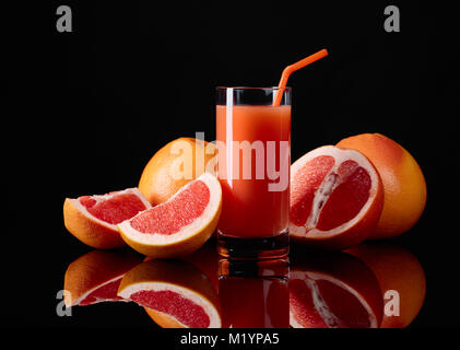 Verre de jus de pamplemousse frais et fruits sur fond noir. Banque D'Images