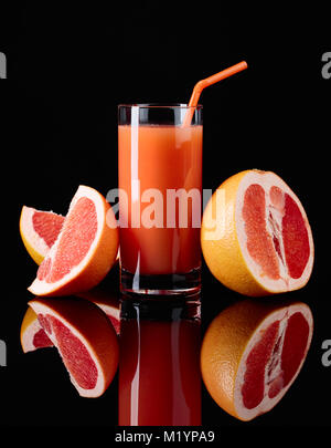 Verre de jus de pamplemousse frais et fruits sur fond noir. Banque D'Images