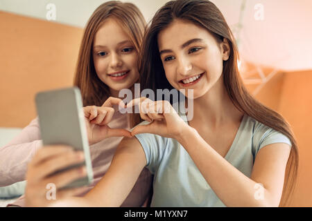 Gorgeous soeurs faire un coeur tout en prenant des selfies Banque D'Images