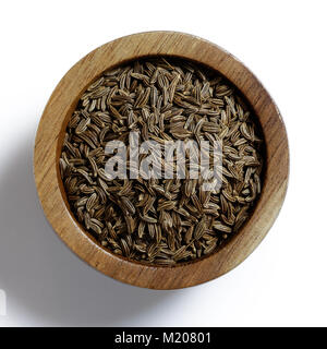 Les graines de cumin ou de carvi à sec dans un bol en bois isolé sur blanc de ci-dessus. Banque D'Images