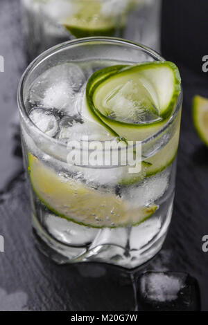 Gin Tonic avec le concombre, citron vert et de la glace dans le verre Banque D'Images