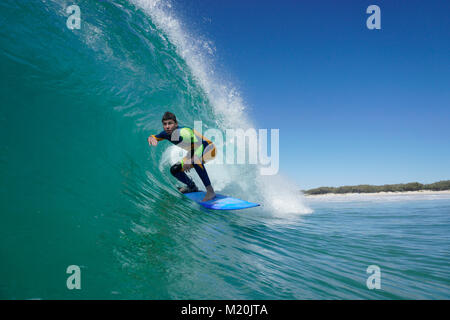Un surfeur monte un baril bleu clair vierge vague à South Stradbroke Island dans l'État du Queensland, Gold Coast, en Australie. Banque D'Images