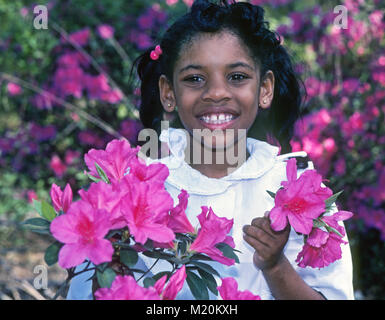 A ten year old African American girl picking azaelas dans le jardin d'une maison antibellum à Eufaula, Alabama. Banque D'Images