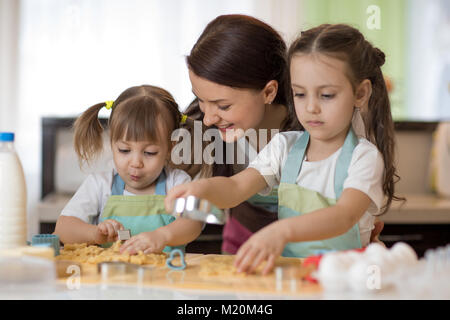 Mère de famille heureuse et ses enfants sont en train de préparer la pâte, faire cuire des biscuits dans la cuisine Banque D'Images