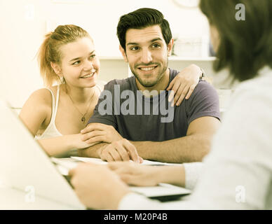 Young smiling couple consulting avec des agents immobiliers home intérieur Banque D'Images