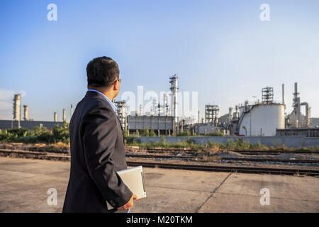 Businessman checking autour de l'usine de raffinerie de pétrole avec un ciel clair Banque D'Images