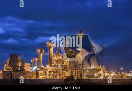 Double exposition de businessman checking des usines de l'industrie des raffineries de pétrole par comprimé le soir comme concept de l'énergie et de la technologie Banque D'Images