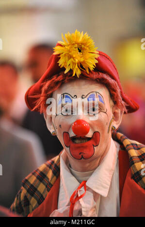 Un clown portant un chant de tournesol à la 67e assemblée annuelle de l'Église au service de clown Grimaldi Holy Trinity Church, Dalston, East London. Le service, qui a été une tradition annuelle depuis 1946, est conservé dans la mémoire de Joseph Clown 'Joey' Grimaldi (1778-1837), le plus célèbre clown anglais qui est né et a joué dans Londres. L'unique service de l'église a lieu le premier dimanche de chaque mois de février et une couronne est posée en l'honneur de Grimaldi. Banque D'Images