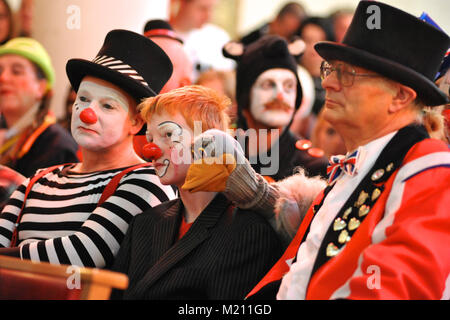 Trois clowns (une avec une marionnette) écouter le service au cours de la 67e assemblée annuelle de l'Église au service de clown Grimaldi Holy Trinity Church, Dalston, East London. Le service, qui a été une tradition annuelle depuis 1946, est conservé dans la mémoire de Joseph Clown 'Joey' Grimaldi (1778-1837), le plus célèbre clown anglais qui est né et a joué dans Londres. L'unique service de l'église a lieu le premier dimanche de chaque mois de février et une couronne est posée en l'honneur de Grimaldi. Banque D'Images