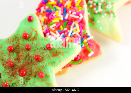 Trois biscuits de Noël décoré avec du glaçage coloré et arrose, et disposés en diagonale et se chevauchaient partiellement sur un fond blanc Banque D'Images