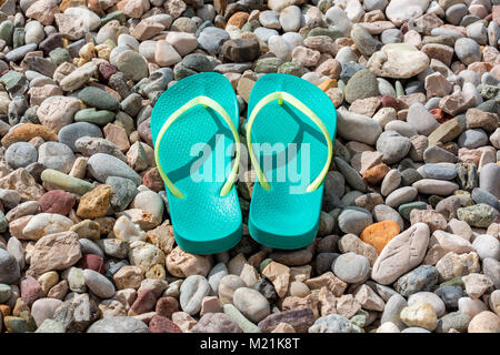 Close up de tongs sur la plage de galets colorés. L'été et vacances Banque D'Images