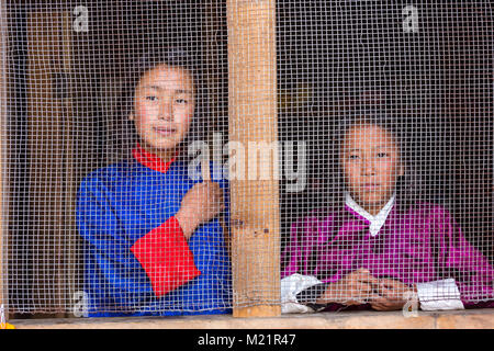 Prakhar Lhakhang, Bumthang, Bhoutan. Les jeunes femmes à la fenêtre de la cuisine à travers l'écran. Banque D'Images