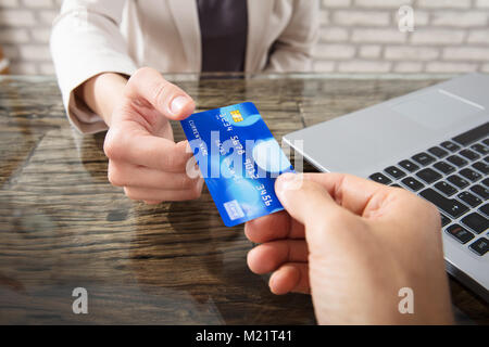 Main d'une personne donnant carte de débit pour Businesswoman At au travail Banque D'Images