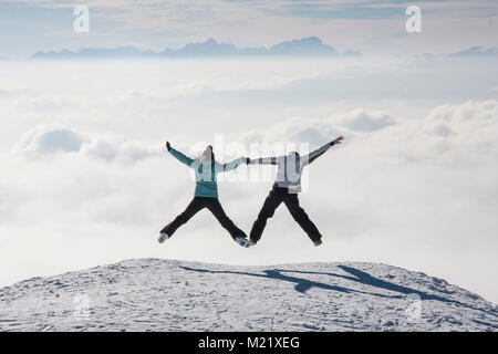 Heureux couple juming au-dessus des nuages dans les montagnes au cours de ski Banque D'Images